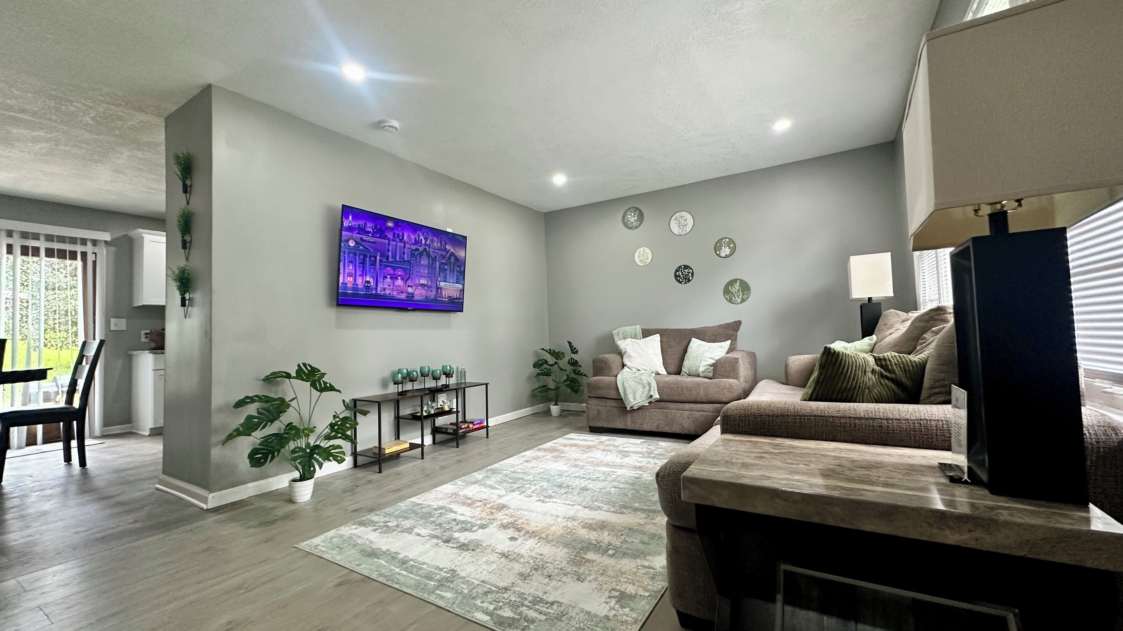 A living room with a flat-screen TV, two sofas, a coffee table, and a dining area with chairs.