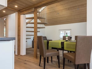 Ein Essbereich mit einer Holztreppe, einem Tisch mit Stühlen und einer Weinflasche.