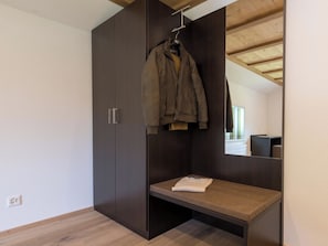 Ein Zimmer mit Kleiderschrank, Bank und einer Garderobe.