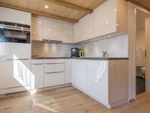 Eine moderne Küche mit weißen Schränken, einem Edelstahl-Kühlschrank und einer Kaffeemaschine.