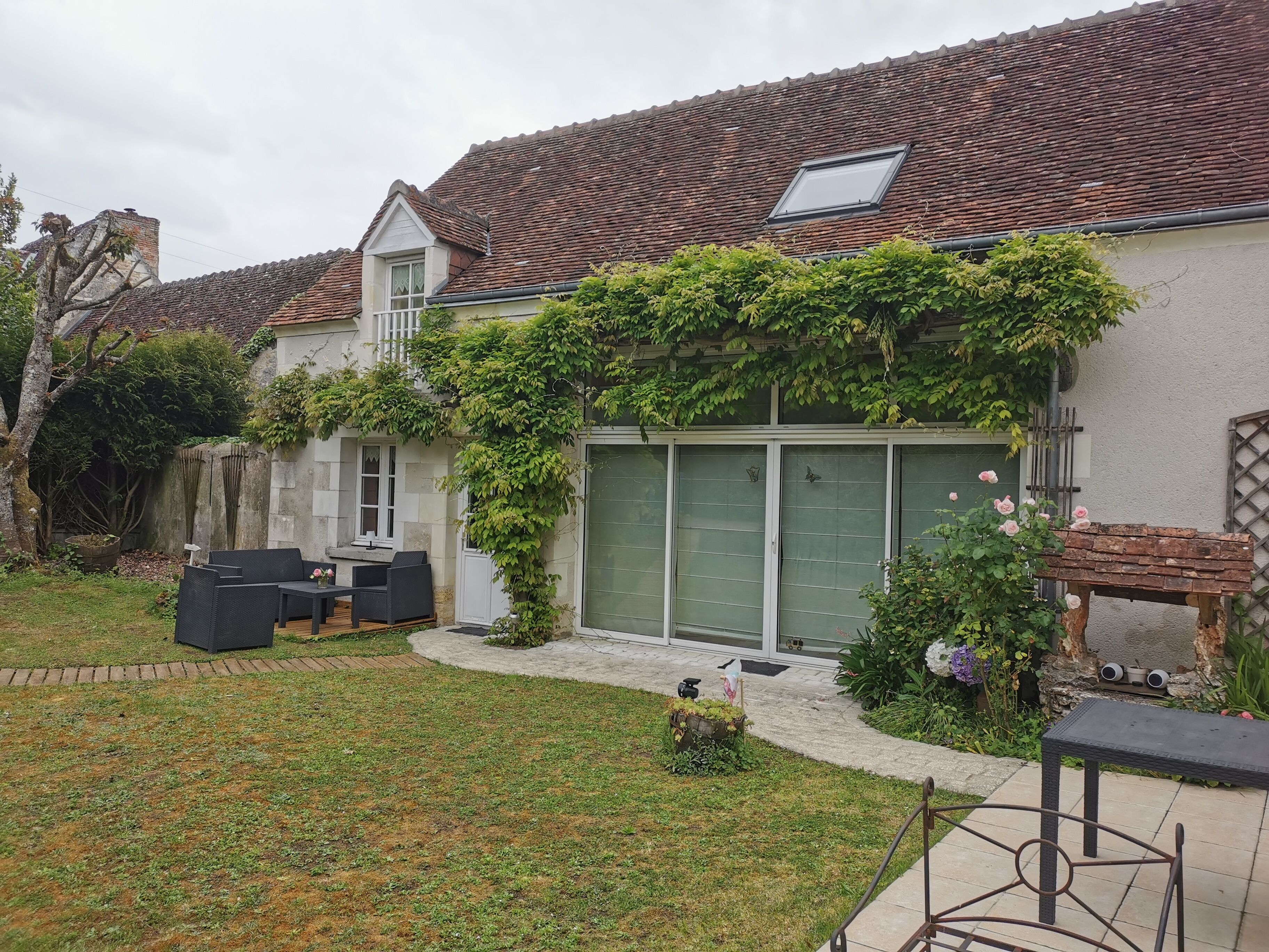 A residential property with a covered patio, outdoor seating, and a garden area.