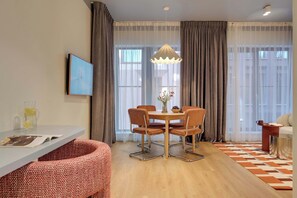 A modern living room with a dining area, featuring a table with chairs, a sofa, a coffee table, and a large window with curtains. - Granaria B104 | TOP Location (Gdańsk)