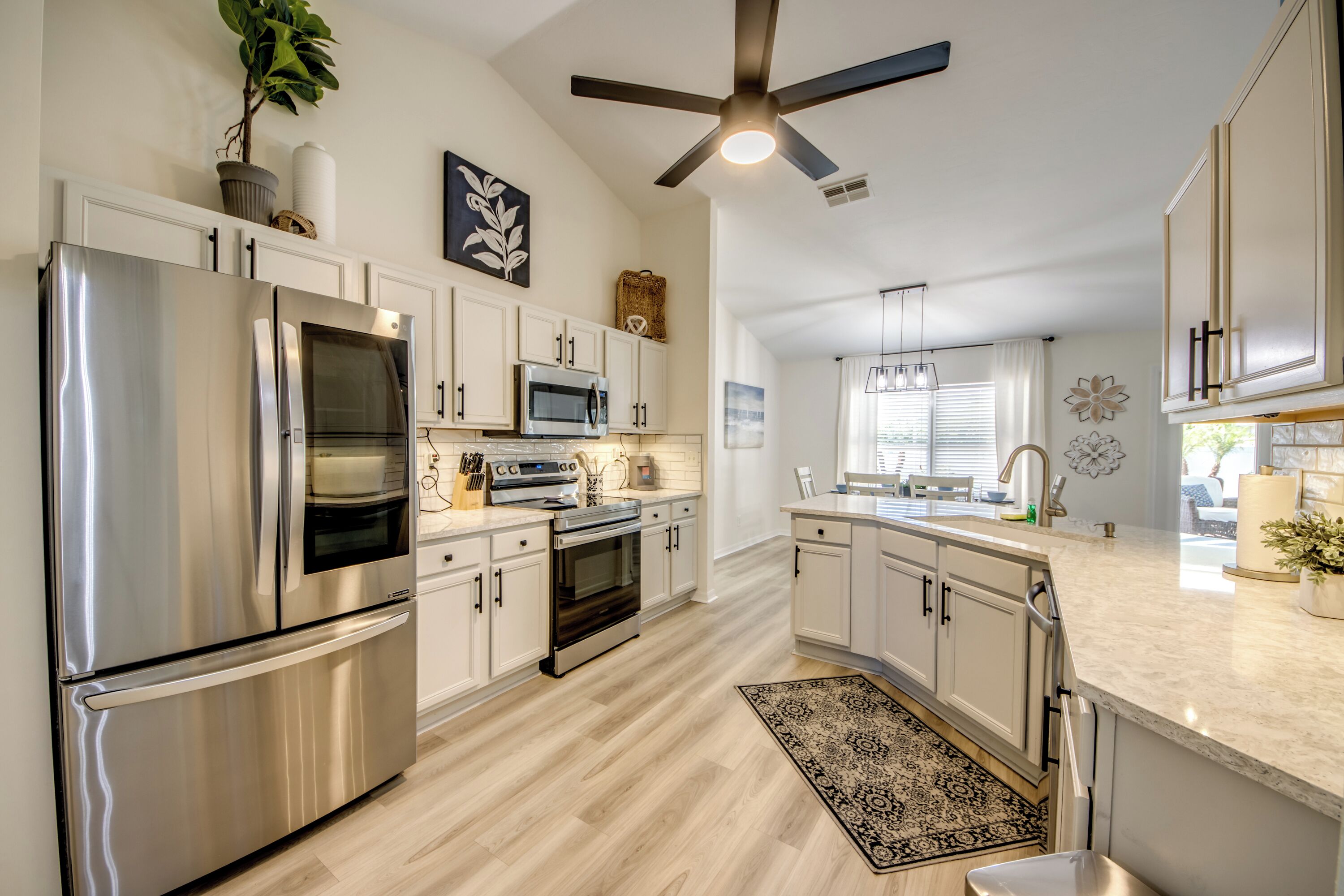A modern kitchen with stainless steel appliances, white cabinetry, and a ceiling fan.