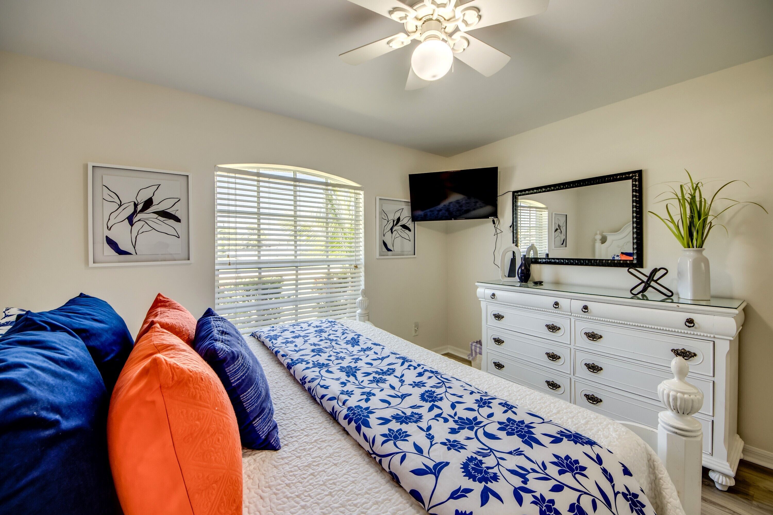 A bedroom with a bed, a dresser, a television, and artwork on the walls.