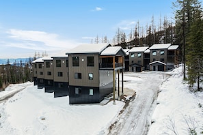 A modern ski resort with multiple buildings, a snow-covered landscape, and a clear sky. - Paradise Condo 100,Hot Tub,Mtn.Views, Lift .5 Mile (Sandpoint)