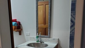A bathroom with a wooden vanity, a sink, a mirror, and a towel rack with towels.