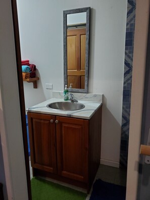 A bathroom with a wooden vanity, a sink, a mirror, and a towel rack with towels.