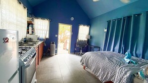 A room with a bed, a desk, a chair, a window, and a door leading outside.