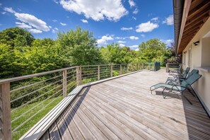 A wooden deck with a railing, surrounded by lush greenery and trees, with a clear sky above. - Large house for 12 people with 2 vacation apartments - 220 m² - 10 beds (Meurthe-et-Moselle)