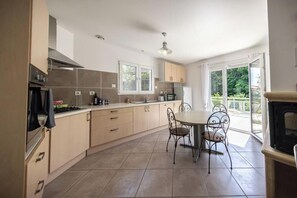 Eine moderne Küche mit Essbereich, großen Fenstern und einem Kamin.