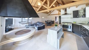 Una cocina moderna con una estufa grande, un comedor con mesa y sillas, y una sala de estar con sofá y chimenea.