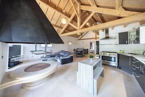 Eine moderne Küche mit einem großen Herd, ein Essbereich mit Tisch und Stühlen sowie ein Wohnbereich mit Sofa und Kamin.