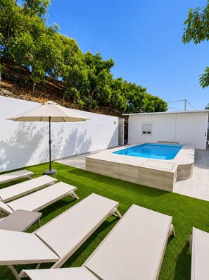 A modern outdoor pool area with a hot tub, surrounded by artificial grass and white lounge chairs. - Casa Jimena in Nerja | Private Pool, 4 Bedrooms & Views (Nerja)