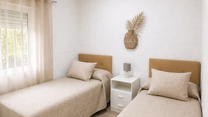 A room with two beds, a nightstand, a lamp, and a decorative wall piece. - Casa Jimena in Nerja | Private Pool, 4 Bedrooms & Views (Nerja)