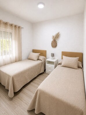 Ein Zimmer mit zwei Betten, einem Nachttisch, einer Lampe und einer Wanddekoration.