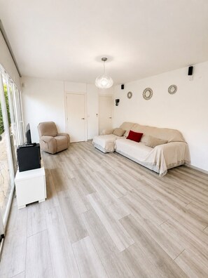 Ein modernes Wohnzimmer mit einer Couch, einem Sessel und einem Fernseher auf einem Schrank.