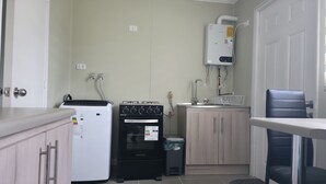 A compact kitchen with a refrigerator, oven, and water heater. - A Peaceful Retreat in Bosquemar (Los Lagos)