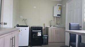 Uma cozinha compacta com geladeira, forno e aquecedor de água.
