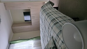 A room with a bed, a small window, and a wall-mounted television. - A Peaceful Retreat in Bosquemar (Los Lagos)