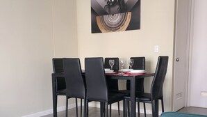 A dining area with a table set for four, black chairs, and a painting on the wall. - A Peaceful Retreat in Bosquemar (Los Lagos)