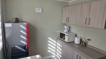 A compact kitchen with a refrigerator, microwave, and cabinets.