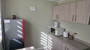 A compact kitchen with a refrigerator, microwave, and cabinets.