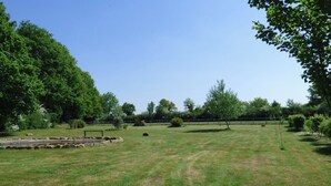 A grassy field with trees and a stone structure.
