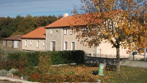 Une maison à deux étages, dotée d’une façade en pierre et d’un toit recouvert de tuiles rouges.