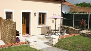 Une maison dotée d’un patio, d’une antenne parabolique et d’un petit jardin.