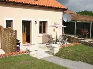 Ein Haus mit einer Terrassenfläche, einer Satellitenschüssel und einem kleinen Garten.