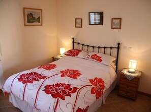 Une chambre à coucher avec un lit, deux tables de chevet et des tableaux accrochés au mur.