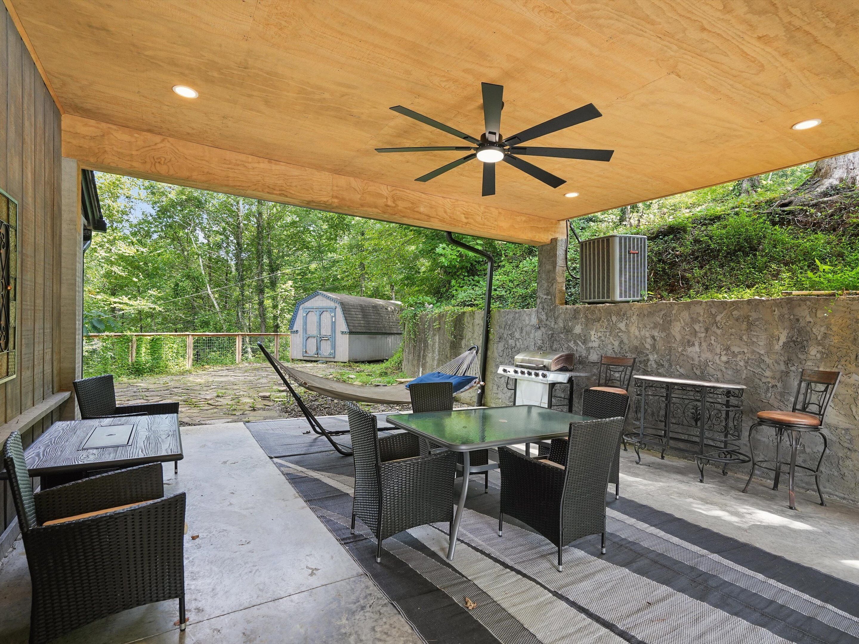 Eine Terrasse im Freien mit Deckenventilator, Grill und Korbmöbeln.