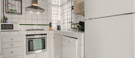 A kitchen with white cabinets, a microwave, an oven, a dishwasher, and a gas stove.