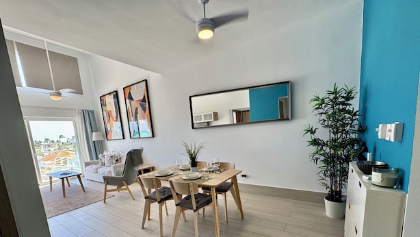 Un comedor moderno con una mesa preparada para cuatro, un sofá y un ventilador de techo.