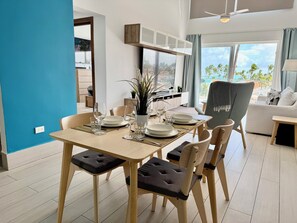 A dining area with a table set for four, chairs with cushioned seats, a potted plant, and a view of the outdoors. - Gold Coast Luxury Sea View, High-End Amenities (Punta Cana)