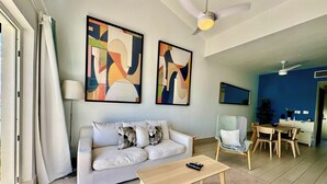 Una sala de estar con sofá, mesa de centro y una obra de arte en la pared.