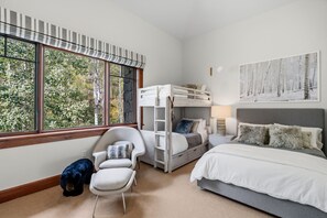 A bedroom with a bunk bed, a desk, a chair, and a bed. There is a window with a view of trees. - Private Luxury Condo by InvitedHome | Ski-In/Ski-Out, Fireplace, Deck Views (Avon)