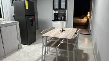 Una cucina compatta con frigorifero, forno a microonde e tavolo con sedie.
