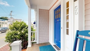 Una casa amb una porta blava, el número '56' a la paret i un petit porxo amb un estriat blau.