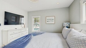 A bedroom with a bed, dresser, television, window, and artwork. - The Ultimate Group Escape on Marthas Vineyard (Oak Bluffs)