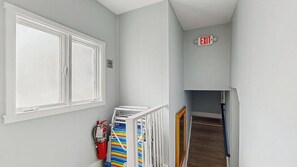 A hallway with a fire extinguisher, a striped towel, and an exit sign. - The Ultimate Group Escape on Marthas Vineyard (Oak Bluffs)
