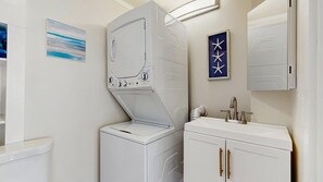 Une buanderie équipée d’un lave-linge et d’un sèche-linge à chargement frontal, d’un évier avec un miroir et d’un meuble avec des tiroirs.