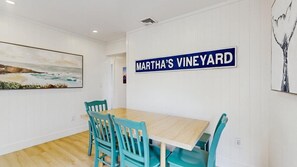 Ein Essbereich mit einem Holztisch und blaugrünen Stühlen, einem Bild an der Wand und einem Schild mit der Aufschrift 'Martha's Vineyard'.