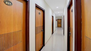 Un corridoio d'albergo con porte in legno, ognuna contrassegnata da un numero.