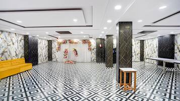 Un vestíbul d'hotel modern amb un paviment de disseny geomètric, un sofà groc i un arranjament floral.