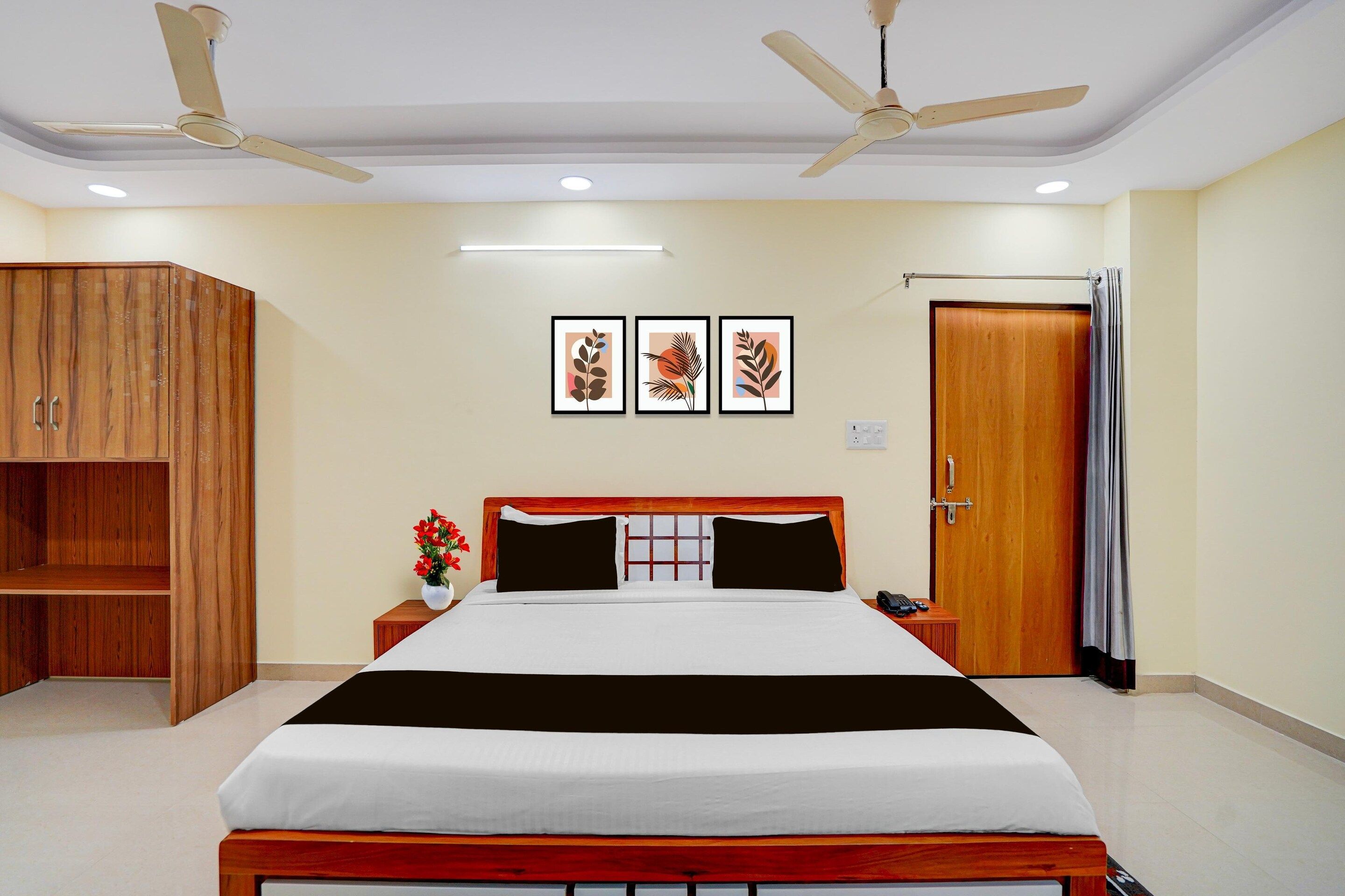 Habitación de hotel con cama, armario, mesita de noche, escritorio, teléfono y puerta con cortinas.