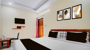 Una camera d'albergo con un letto, una televisione a parete e tre quadri appesi sopra il letto.