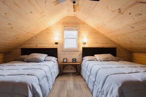 Een knus slaapkamer op zolder met twee bedden, houten wanden, een schuine plafond en een raam.