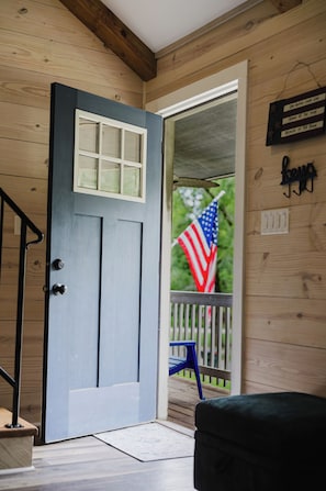 Een houten deur met een raam, een veranda met een stoel en een Amerikaanse vlag.