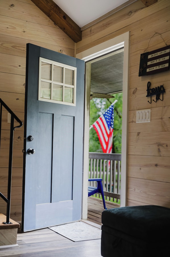 A wooden door with a window, a porch with a chair, and an American flag. - Lakeside Retreat near Hot Springs - Swim & Unwind (Hot Springs)